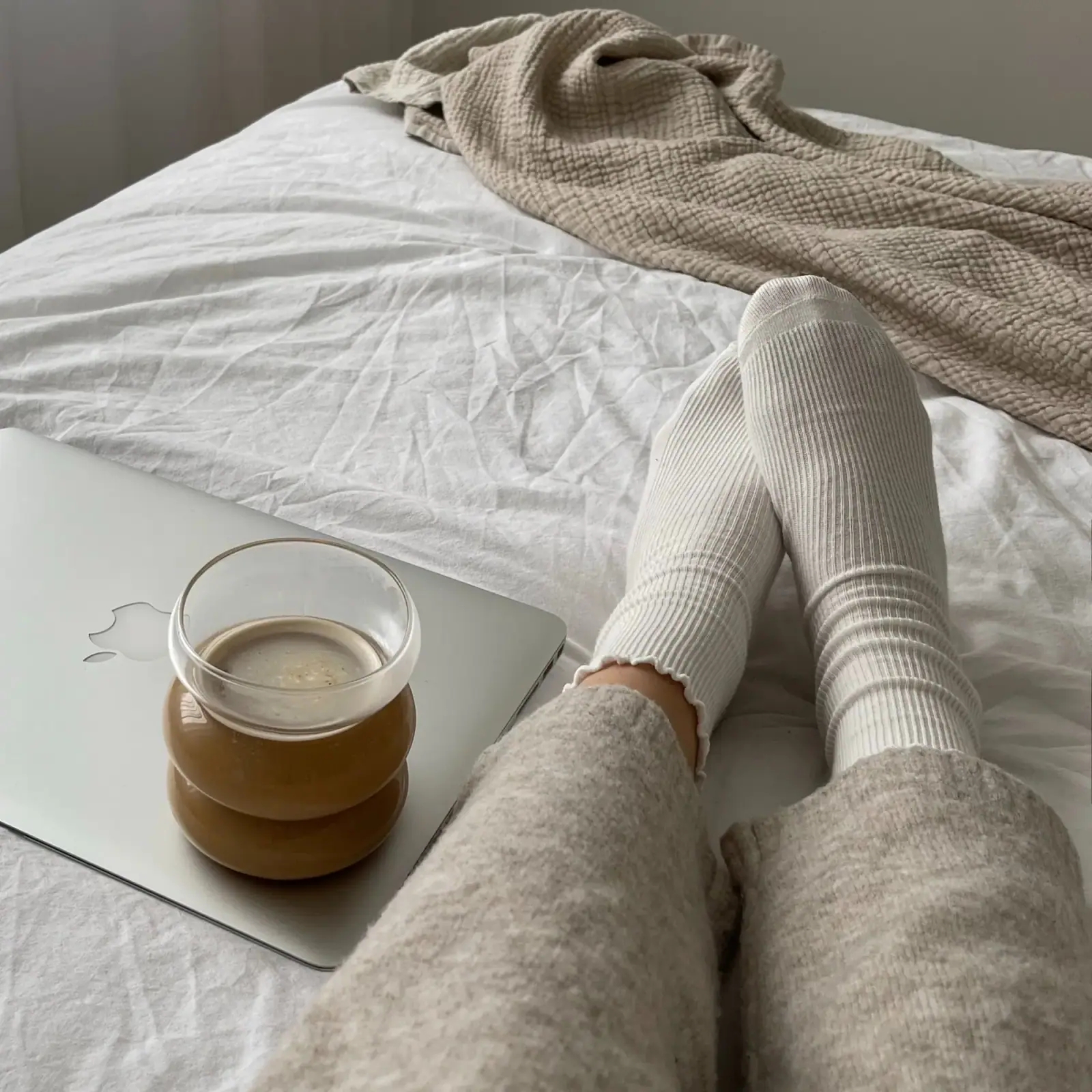 Person wearing light socks while relaxing on a bed